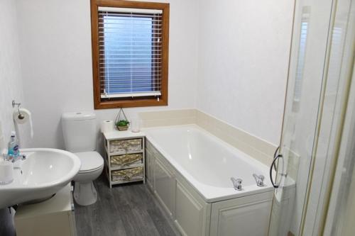 a bathroom with a tub and a toilet and a sink at Newly Refurbished 2 Bedroom flat on NC500 route in Wick