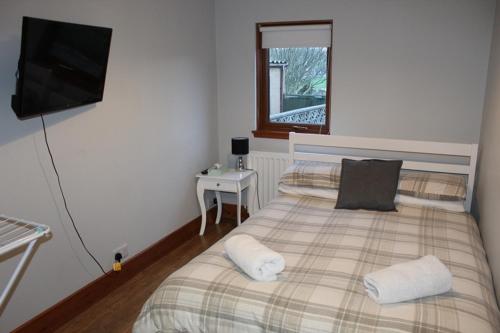 een slaapkamer met een bed met 2 kussens en een televisie bij Newly Refurbished 2 Bedroom flat on NC500 route in Wick