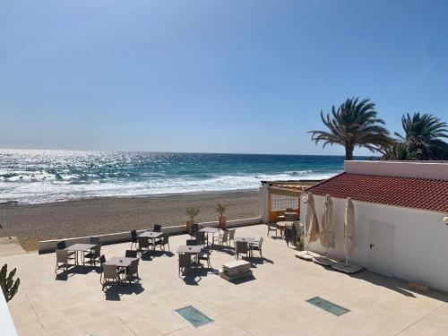a patio with tables and chairs on the beach at Hospedium Hotel Continental in Mojácar