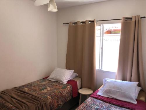 Casa Exclusiva a 400 Metros da Praia em Manguinhos - Condomínio com Vigilância 24hs في سيرا: غرفة صغيرة بسريرين ونافذة