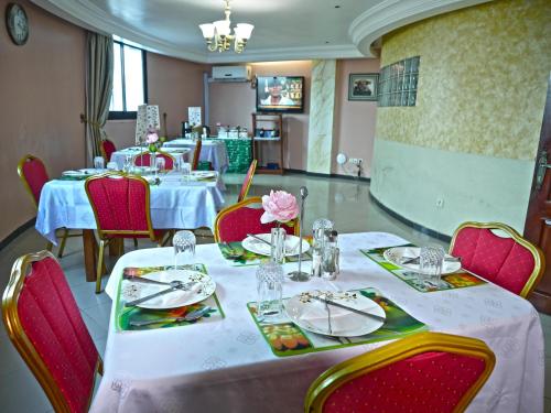 una sala da pranzo con tavoli e sedie con tovaglie bianche di Residence Le Carat a Douala