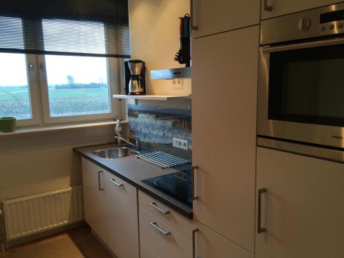 a kitchen with a stove top oven next to a window at Apartment Zonnehoek in Aagtekerke