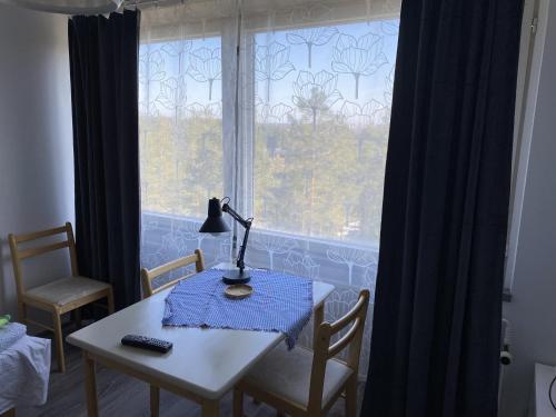 une table avec une lampe devant une fenêtre dans l'établissement Kumpukuja apartment, à Kouvola