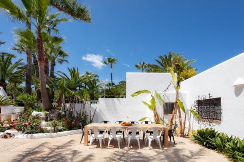 CAN TEO - Holiday Villa in Ibiza في مدينة إيبيزا: طاولة وكراسي على الشاطئ مع أشجار النخيل