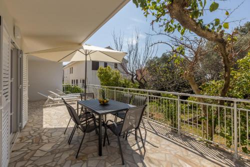 a table and chairs on a balcony with an umbrella at Seaside Sanctuary - Modern 3 Bedroom and 3 Bathroom Apartment 60m from Beach in Novalja