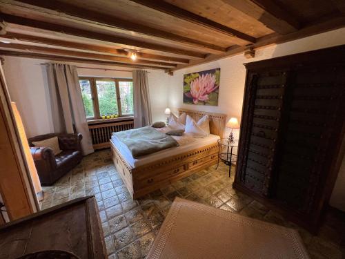 a bedroom with a bed and a chair and a window at Alpen Suite Tegernsee - große Sonnenterasse und idyllischer Garten in Bad Wiessee