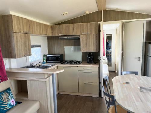 a kitchen with wooden cabinets and a table at Camping De Collignon in Cherbourg en Cotentin