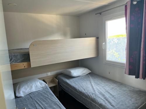 um pequeno quarto com 2 camas e uma janela em Camping De Collignon em Cherbourg en Cotentin