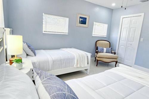 1 dormitorio azul con 2 camas y 1 silla en Paradise Vacation Home, en Boynton Beach