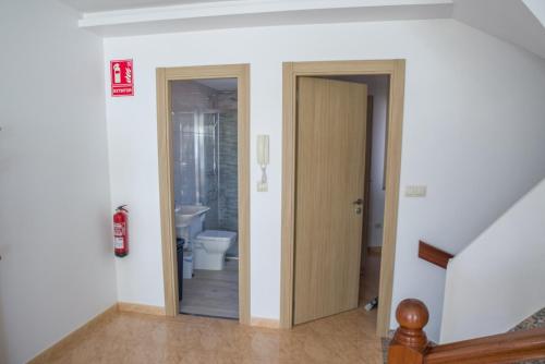 a hallway with a bathroom with a toilet and a door at Apartamentos pilucha in Muxia