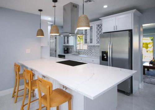 a kitchen with a white counter top and wooden chairs at Paradise Vacation Home in Boynton Beach