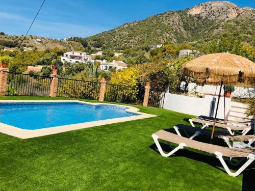 a swimming pool with a umbrella and two chairs and a table at El Nido Frigiliana - Cortijo Rosalia in Frigiliana