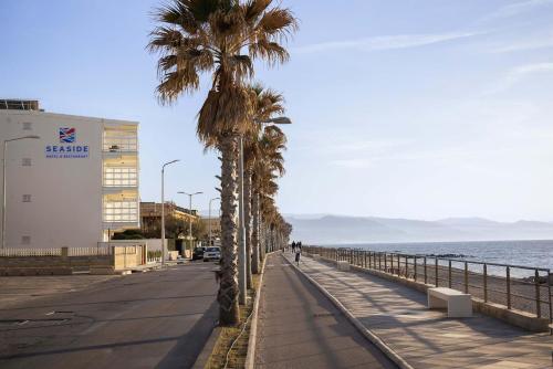 a sidewalk with palm trees next to the ocean at Seaside Hotel in Capo dʼOrlando