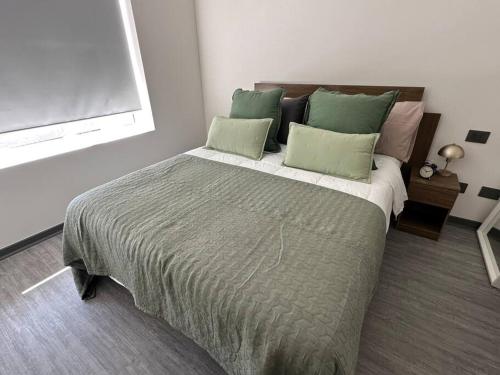 a bedroom with a large bed with green pillows at Depto 1H 1B con Balcón, excelente conectividad in Santiago