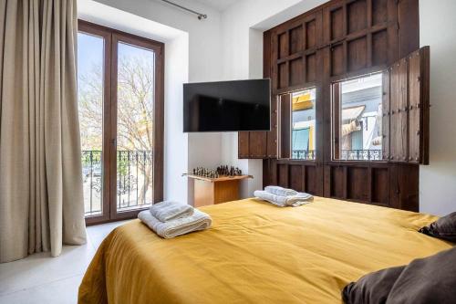 a bedroom with a large yellow bed with a flat screen tv at Apartamento exclusivo con vistas únicas en triana in Seville