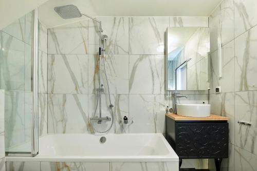 a bathroom with a tub and a sink and a mirror at Apartament Bursztynowy Piec in Hel
