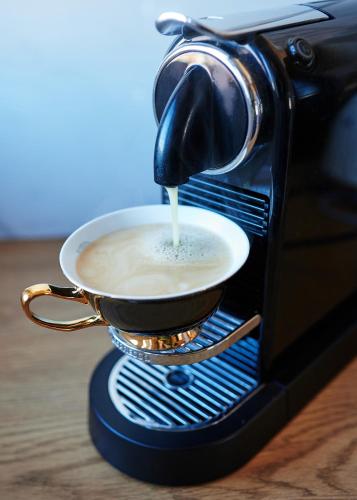 a cup of coffee being poured into a toaster oven at Apartament Bursztynowy Piec in Hel