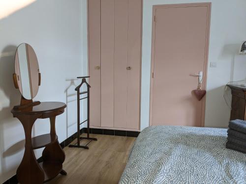 a bedroom with a bed and a dressing table and a mirror at Au chalet d'Illiers Combray, grand jardin arboré in Illiers