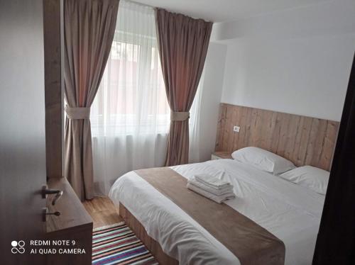 een slaapkamer met een bed en een raam met gordijnen bij Apartament Cristina in Borşa