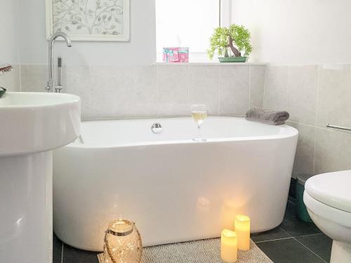 a white bath tub in a bathroom with candles at Christmas Cottage in Cheddar