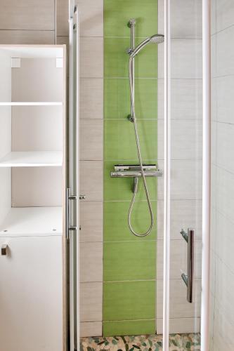 La salle de bains est pourvue d'une douche et d'un mur vert. dans l'établissement 600m plage - Centre ville - appartement pour 4, à Concarneau