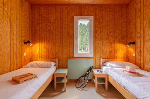Ce lit se trouve dans un dortoir doté de murs en bois et d'une fenêtre. dans l'établissement Azureva Vendée Océan, à Longeville-sur-Mer