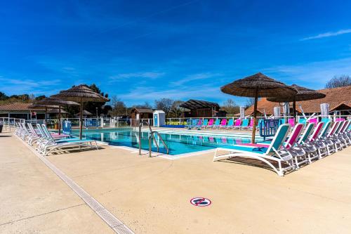 a swimming pool with lounge chairs and umbrellas at Mobilehome familial in Gastes