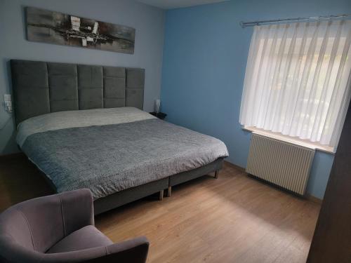 une chambre avec un lit et une chaise dedans dans l'établissement L'Orée du Bois, à Dossenheim-sur-Zinsel