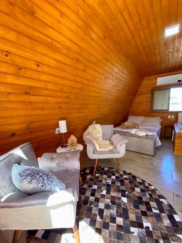 um quarto com sofás e cadeiras num quarto de madeira em Chalés da Serra em São Francisco de Paula