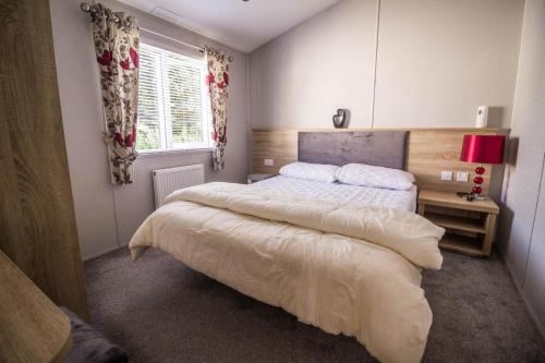 um quarto com uma cama grande e uma janela em Stunning 4 Berth Lodge With Decking At Breydon Water In Norfolk Ref 10094b em Belton