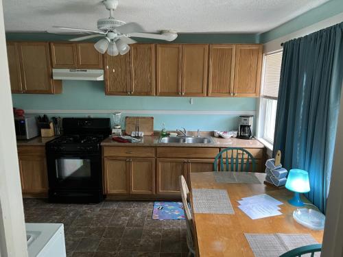 kuchnia z drewnianymi szafkami i stołem z wentylatorem sufitowym w obiekcie Historic Beach Side Getaway - Pet friendly, WiFi cottage w mieście Norfolk