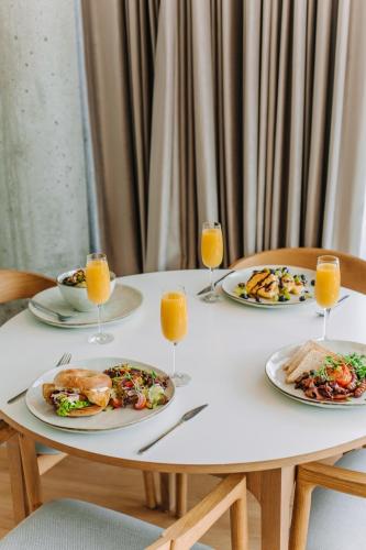 ein Tisch mit Tellern voller Essen und Gläsern mit Orangensaft in der Unterkunft Aparthotel Park - By The Sea in Gdynia