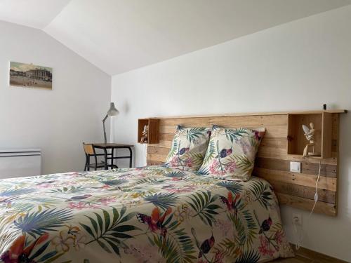 een slaapkamer met een bed met een kleurrijk dekbed en kussens bij L'échappée flamande in Hazebrouck