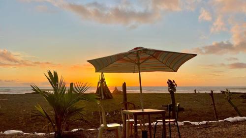 una mesa y sillas bajo una sombrilla en la playa en Villa Luz Ovelia, en El Valle