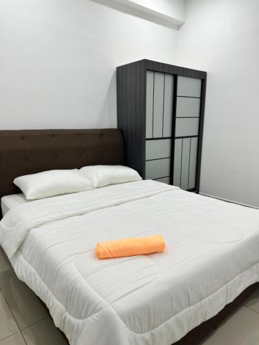 a bed with an orange towel on top of it at Manjung Vermogen Stay-Wi-Fi+KTV(Near Aeon) in Sitiawan