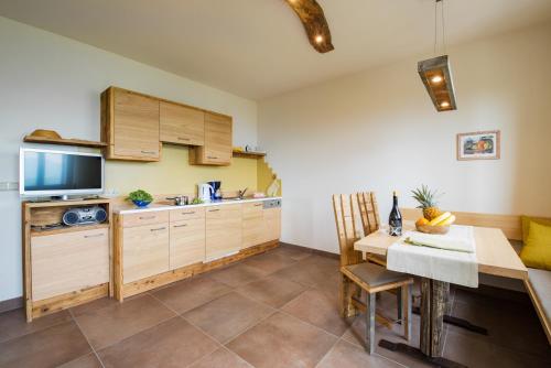 a kitchen with wooden cabinets and a table and a television at Dissertorihof in Caldaro