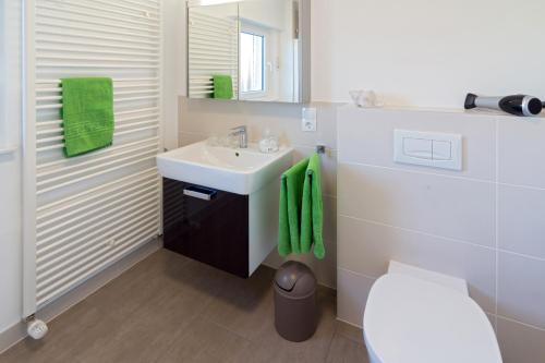a white bathroom with a sink and a toilet at Ferienhaus Neptun Norddeich in Norddeich