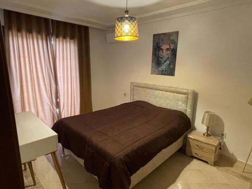 a bedroom with a bed and a table and a lamp at Appartement s2 luxe tunis Jardins de Carthage in Tunis