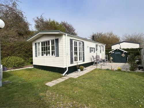 a white tiny house in a yard at ZP 470 - Camping de Zandput in Vrouwenpolder