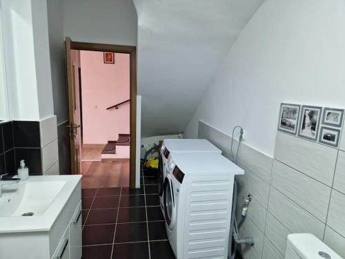 uma casa de banho com um lavatório e uma máquina de lavar roupa em Casă și curte confortabilă em Brasov