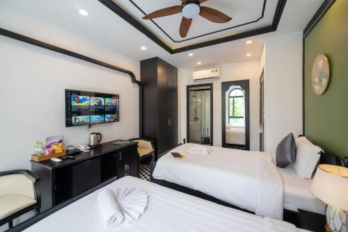 a bedroom with two beds and a ceiling fan at Le Palmier Phu Quoc Hotel - Free Shuttle To Grand World in Phu Quoc