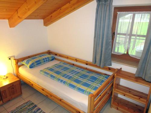 Schlafzimmer mit einem Bett mit einem Holzrahmen und einem Fenster in der Unterkunft Ferienwohnung Sunkler in Waging am See
