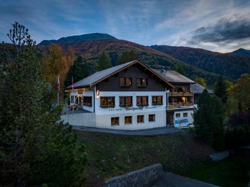 a large white house with mountains in the background at Hotel Restaurant Bürchnerhof in Bürchen