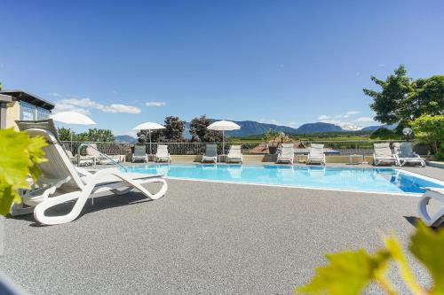 a pool with chaise lounge chairs and a swimming pool at Hotel Alexandres in Appiano sulla Strada del Vino