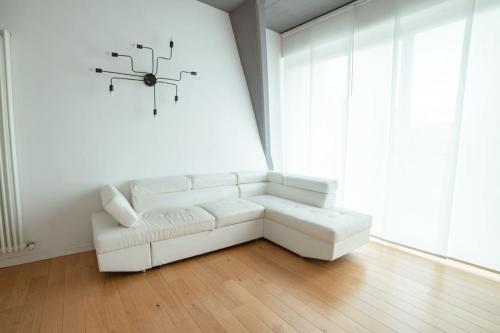 a living room with a white couch and a clock on the wall at Statuto suite in Florence