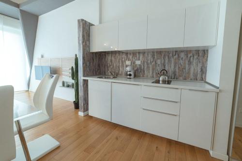 una cucina con armadietti bianchi e pavimenti in legno di 爪ㄚ ㄥㄖ千ㄒ a Firenze