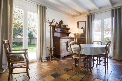 une salle à manger avec une table, des chaises et des fenêtres dans l'établissement Villa PIERROT avec grand jardin arboré, proche du port et des restaurants, à La Flotte
