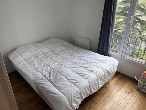 ein weißes Bett in einem Zimmer mit Fenster in der Unterkunft 20 min du Stade de France in Saint-Denis