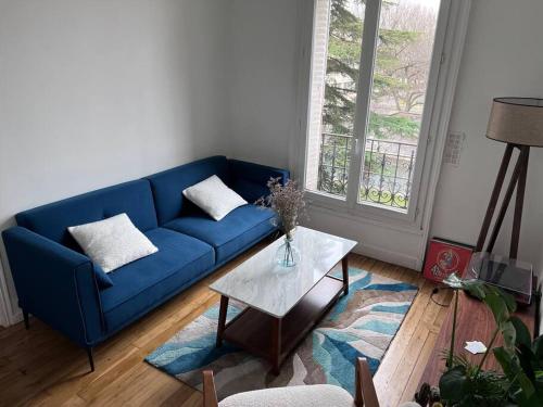 ein blaues Sofa im Wohnzimmer mit einem Tisch in der Unterkunft 20 min du Stade de France in Saint-Denis