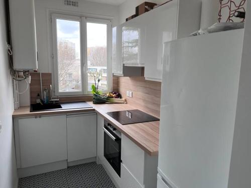a kitchen with white cabinets and a sink and a window at 20 min du Stade de France in Saint-Denis